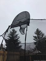 Close-up of black mesh enclosure net with attached basketball hoop and backboard.