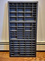 Full front view of the rectangular matte black wooden typeset drawer showing numerous compartments.