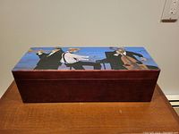 Front view of rectangular wooden box with a painted scene of jazz musicians on lid and stained wood sides.