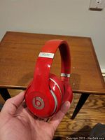 Red Beats by Dre Studio Wireless headphones held showing side ear cup with logo and partial headband.