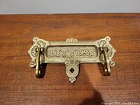 Front close-up photo of vintage brass letter slot flap with ornate edges and 'LETTERS' text visible