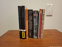 Seven-volume book collection displayed upright on a wooden surface, showing the spines with titles and authors visible.