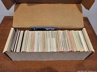 Box open showing a dense row of sports trading cards aligned vertically inside brown storage box.