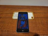 Front view of Apple iPod Touch 5th Gen displaying home screen with Superman wallpaper.