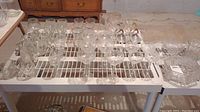 Top view of assorted clear glass stemware and drinking glasses arranged on a rack, including wine glasses and water goblets.