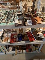 Shelves displaying numerous religious items arranged including rosaries, crucifixes, statues, small religious memorabilia and a candle.