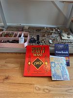 Overview of lot contents showing vintage jewelry, hair accessories, and yearbooks spread on floor