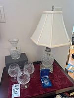 Full view of the Waterford crystal collection items displayed on a table with red runner, includes lamp, decanter, glasses, and ashtray.