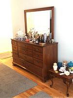 Full view of the Welsh Valley dresser with mirror, surrounded by assorted decorative items on top and adjacent small wooden table.