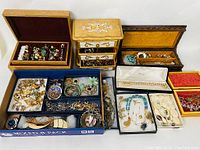 Multiple wooden and cardboard boxes containing assorted jewelry including necklaces, bracelets, rings, earrings and brooches