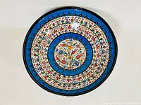 Top view of large ceramic bowl showing intricate multicolored floral pattern with blue background.