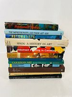Stack of 12 large hardcover art books with varied art topics visible on spine including Canadian Art, Abstract Painting, Impressionists, and Chagall Ceramics Sculptures.