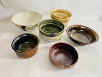 Front view showing six handcrafted pottery bowls in varied colors and glazes.