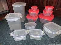 Photo showing entire set of 24 Lock + Lock food storage containers arranged on floor with clear rectangular containers on left and round red topped containers on right.