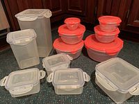 Full set of 24 Lock & Lock food storage containers showing clear plastic containers with white locking lids and round containers with red lids, stacked and arranged for view