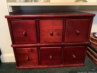 Front view of red cherry finish apothecary style solid wood storage cabinet with six drawers and round knobs.
