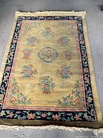 Full view of the Ethan Allen vintage area rug showing the creamy yellow color and floral motifs with contrasting dark blue floral border.
