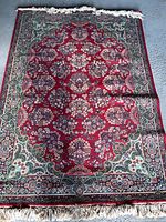 Full view of Ethan Allen area rug showing overall pattern and size with fringe edges and slight wrinkles.