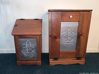 Front view showing the smaller potato bin with hinged lid and larger trash bin with hinged front door and knob, both with embossed tin fruit basket panels.