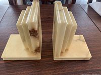 Pair of marble bookends facing forward showing stepped vertical panels and flat base with cream and brown marble coloring.