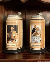 Front view of two Norman Rockwell Four Freedoms beer steins showing detailed artwork and identifying text.