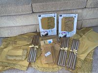 Display of all vintage gold table linens folded and grouped by shade with bundles of gold taper candles and boxed items.
