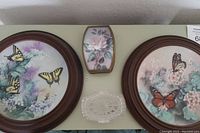 Photo showing two framed butterfly collector plates and two trinket boxes arranged side by side.