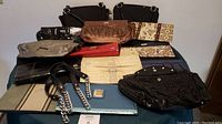 Overall lot photo showing 2 Miche purses, 10 different purse covers, and spare handles on a table.