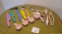 Overall display of the pink Cuisinart kitchen utensil set showing all items including knives, measuring cups, pasta server, tongs, and cutters.