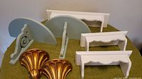 Lot contents showing three white wooden shelves, three pairs of gray-blue wooden shelf brackets, and two gold finial decorations.