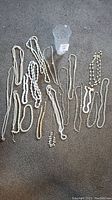Photo showing a collection of white and cream necklaces with faux pearls and some crystal beads on a carpeted surface.