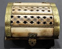 Top view of a small rectangular curved trinket box with bone panels hand carved with circular and star shaped cut patterns and bordered with brass.