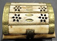 Close-up front view of rectangular bone trinket box showing perforated floral designs and brass bead borders on lid.