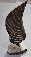 Front angled photo showing curvature and grooved details on the hardwood sculpture, emphasizing its shape and texture.
