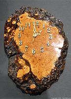 Front view of the large burrow wood clock showing the natural polished wood face, metal numerals, and clock hands stopped at 12:04.