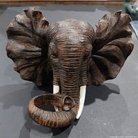 Front view of the large resin elephant head figure showing texture, ears, tusks, and curled trunk.