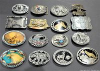 Full lot photo showing all 16 belt buckles in a group on black background.