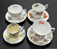 Front view of 4 tea cup and saucer sets with different floral designs and gold rim accents, one with Alberta printed inside.