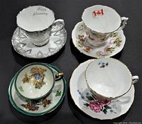 Top view of four assorted tea cup and saucer sets showing varying floral and commemorative designs and shape details