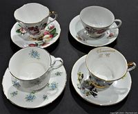 Top view showing the set of 4 tea cups on matching saucers with varied floral patterns and gold trim.