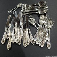 Full set of assorted knives, forks, soup spoons, and teaspoons arranged on black background showing silverplate flatware condition and style.