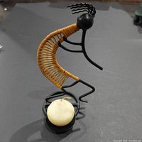Front view of unique figure candle holder with round white candle in front