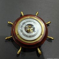 Full front view of the Weather Guide barometer showing wooden ship wheel frame and dial with weather condition markings