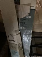 Photo of two boxes containing white window blinds, showing brand and size information.