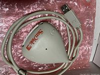 Front view of the triangular SanDisk ImageMate card reader with USB cable on a pink bubble wrap surface.