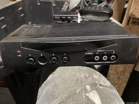 Front view of a black AV selector box with four input buttons and RCA/S-Video ports
