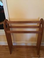Full front view of the vintage wooden blanket stand showing the two horizontal bars and rounded side cutouts.
