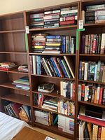 Full frontal view of the Ikea bookshelf filled partially with assorted hardcover and paperback books. Shows the wood veneer finish and shelf layout clearly.