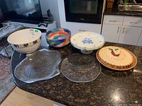 Overview of six bowls and platters including ceramic and glass items on kitchen countertop
