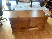 Front angled view of the medium brown wooden chest showing two paneled doors and top surface with some scratches.